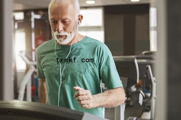 Senior man running on treadmill while listening to music